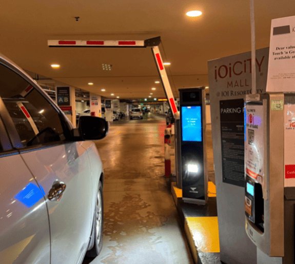 Car approaching parking gate with ANPR camera reading license plate